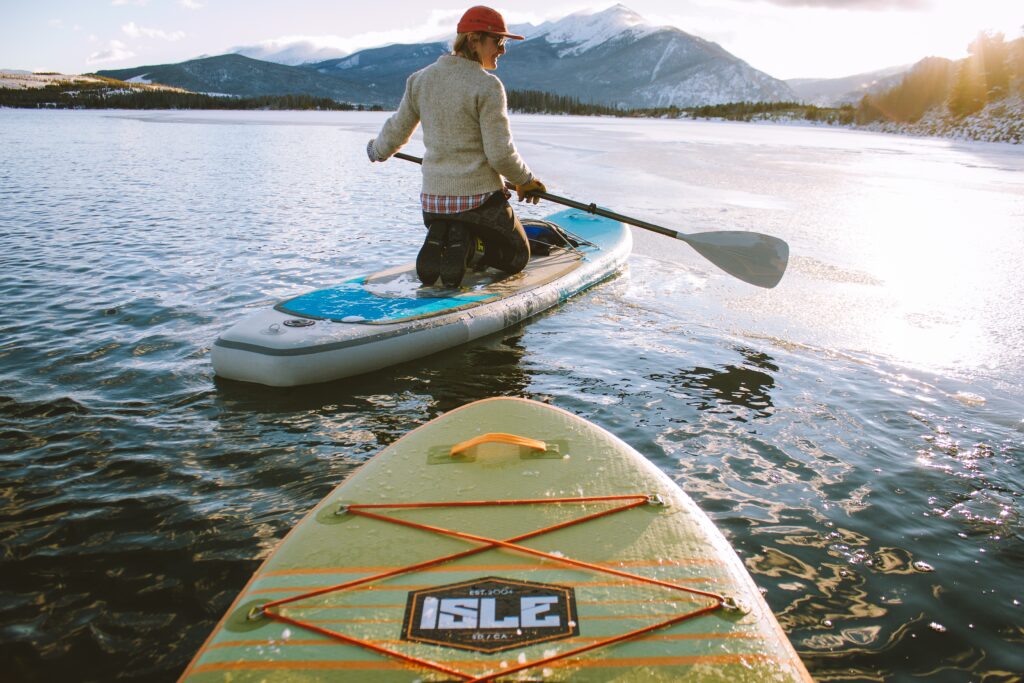 Beautiful shot of a male sitting on a paddleboard holding an oar with mountains in the background